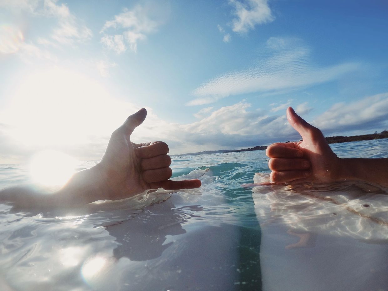Two Mentawai Surfers on Surfboards giving each other a thumbs up.