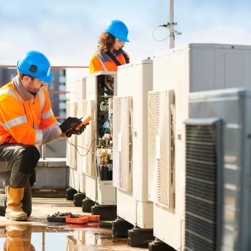 Technicians inspecting HVAC units outdoors.