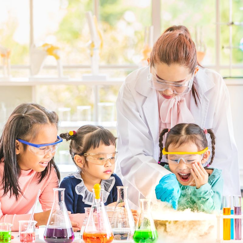 Science teacher teach Asian students in laboratory room, smoke float out of bowl, they excited, colorful test tube and microscope on table in laboratory room, concept for study in laboratory room.