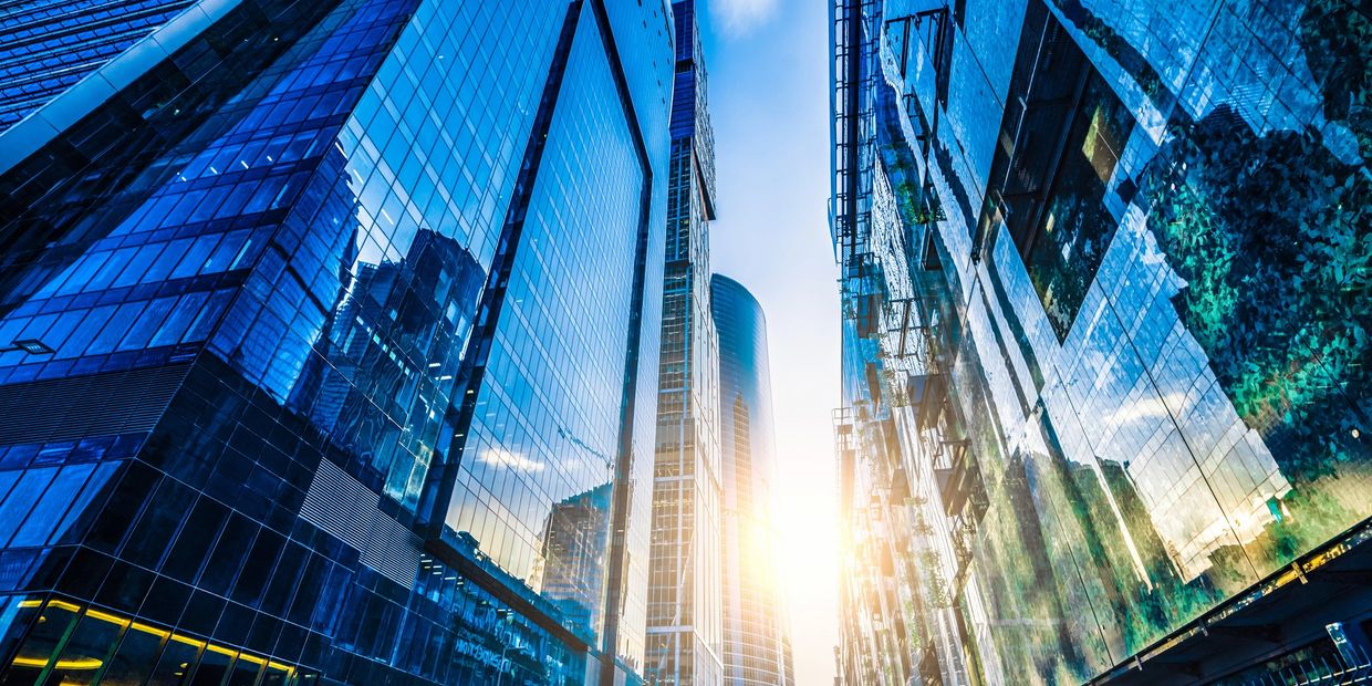 Modern cityscape with glass buildings and empty plaza at sunset.