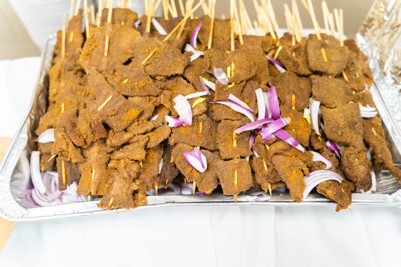 Nigerian pepper beef suya on stakes at party - a popular snack