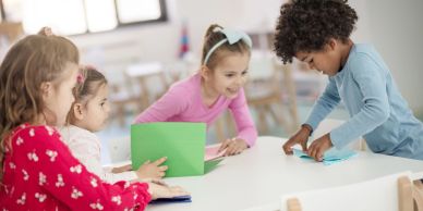 Children happily doing crafts together in a bright room.