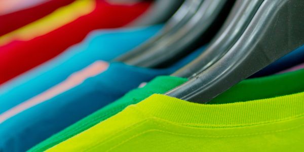 Colorful t-shirts neatly hung on black hangers in a row.