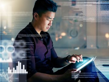 Man interacting with a futuristic digital tablet displaying data visuals.