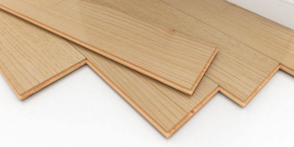 Light wood laminate flooring planks arranged on a white surface.