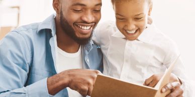 Father and daughter happily reading a book together.