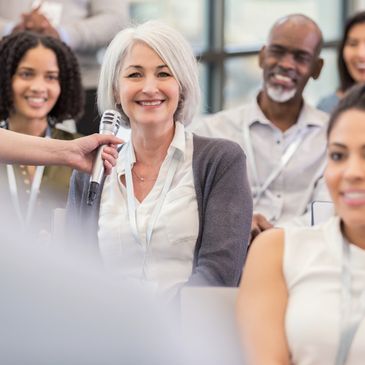A diverse group of adults smiling during a discussion or seminar.