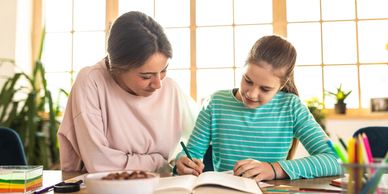 Woman helping girl with homework.