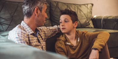 A father and son have a heartfelt conversation on the floor.