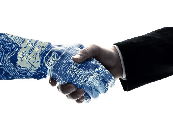 A human hand shakes a robotic hand with a circuit design.