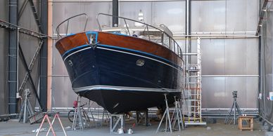 A classic wooden boat undergoing maintenance indoors.