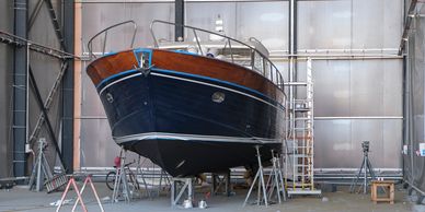 A classic wooden boat undergoing maintenance indoors.