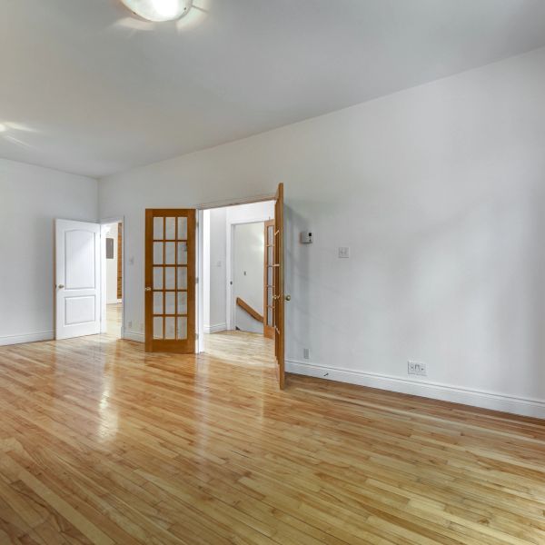 Empty room with wooden floors and glass-paneled doors.