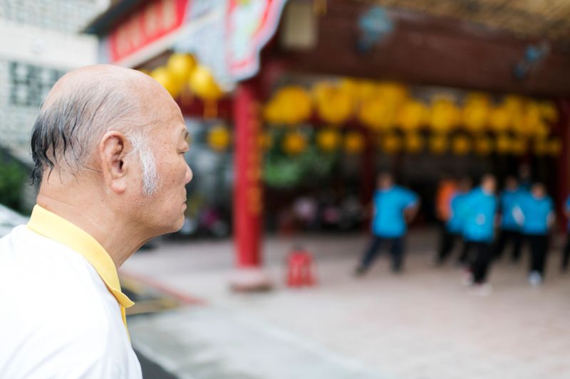 Side view of senior Tai Chi master watching students practice