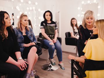Women watching a makeup session in a studio.