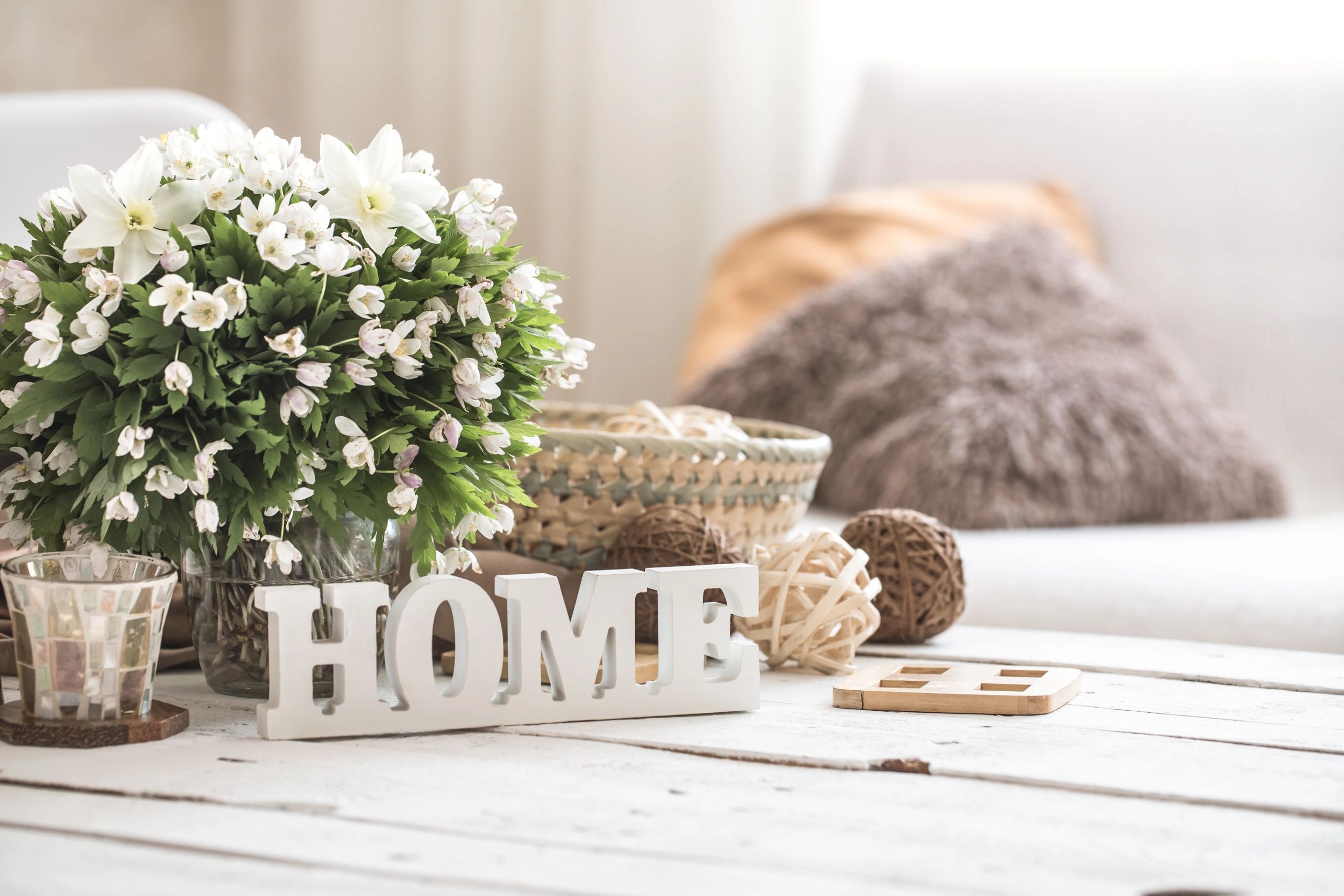 Cozy home decor with flowers and wooden letters spelling HOME on a rustic table.