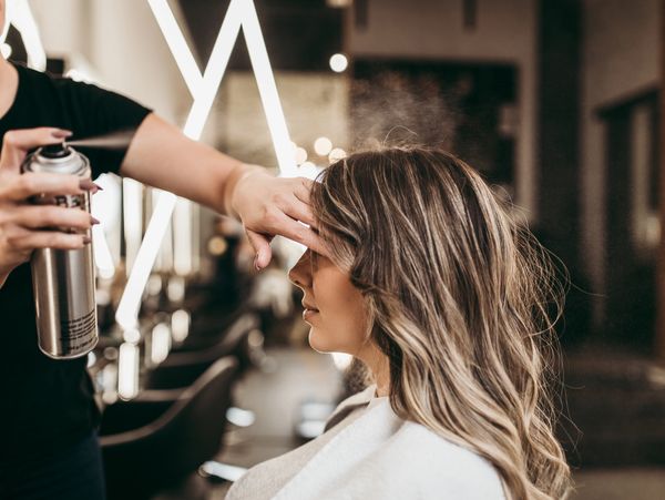 Woman getting hairspray applied in a salon.