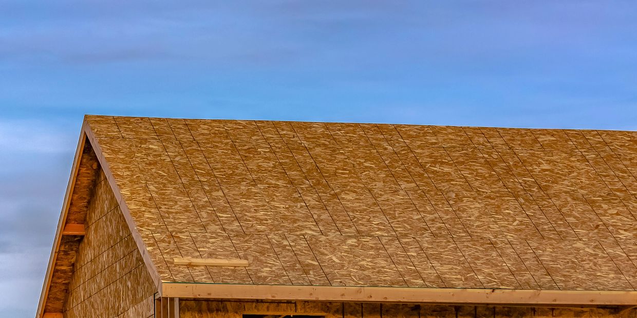 A wooden roof under construction against a clear blue sky.
