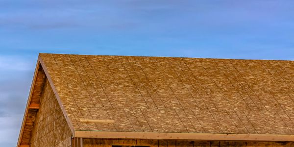 A wooden roof under construction against a clear blue sky.