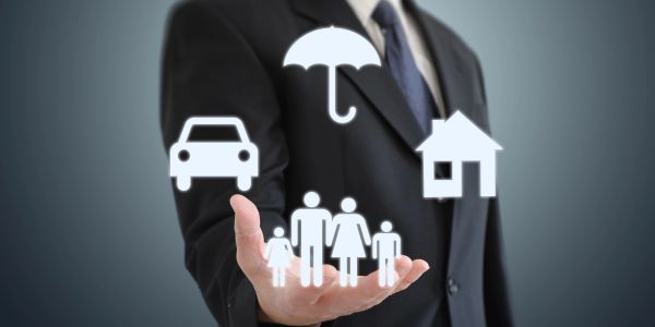 Businessman holding icons for car, family, umbrella, and house.