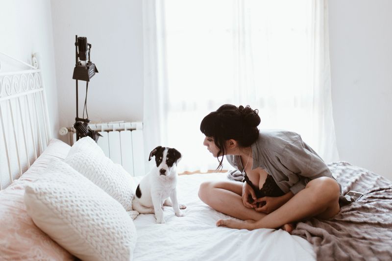 beautiful brunette woman with her sweet puppy in bedroom