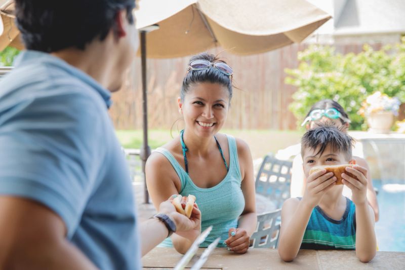 Woman enjoying neighborhood backyard cookout with her young son