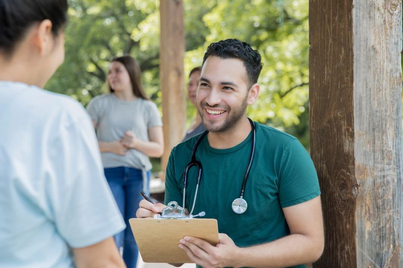 Young healthcare professional assists woman during outdoor health fair clinic event