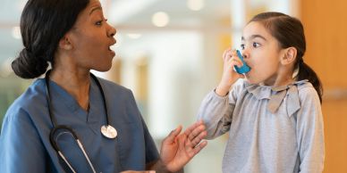 Nurse instructing girl using an inhaler.