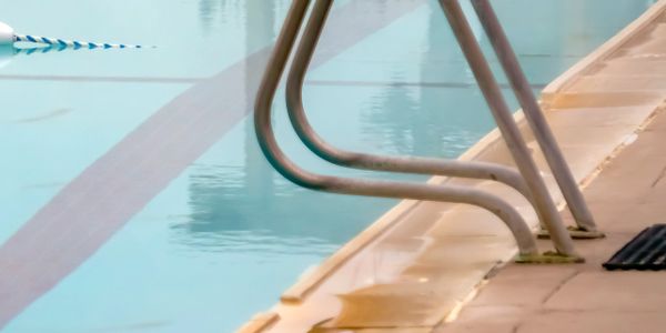 Close-up of a pool ladder at the edge of a swimming pool.