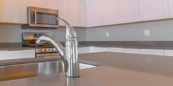 Modern kitchen with sleek faucet and stainless steel appliances.