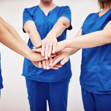 Healthcare workers joining hands in teamwork and solidarity.