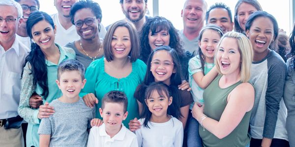 A diverse group of smiling people of different ages posing together.