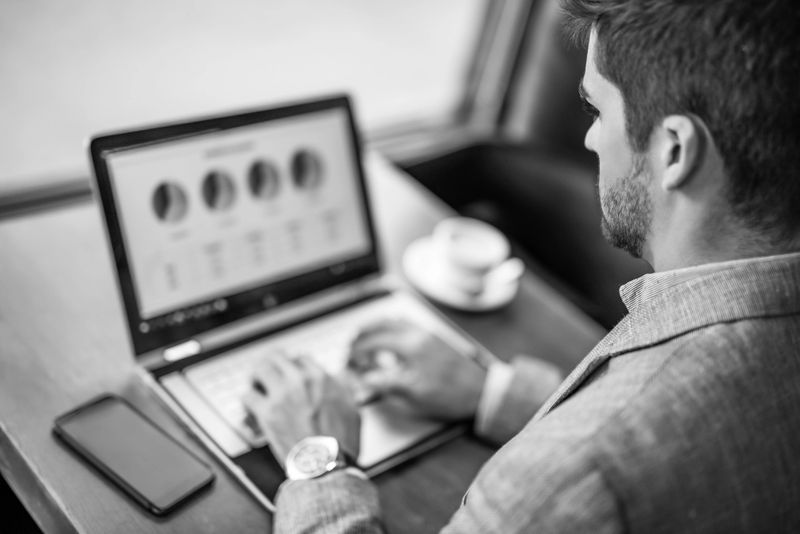 Black and white photo of hard working entrepreneur using laptop in coffee shop.