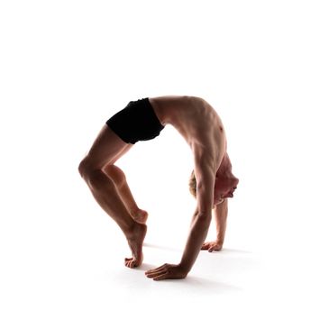 Man performing a backbend yoga pose on toes and hands.