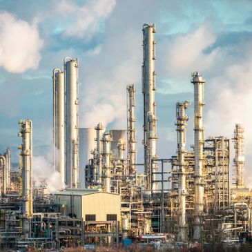 A large industrial refinery with tall distillation towers under a blue sky.
