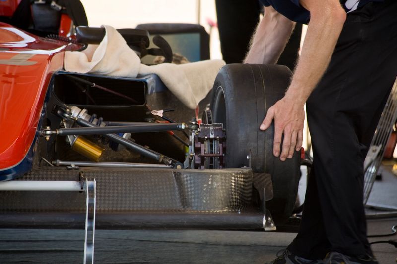 Mechanic putting on tire on race car preparation.
