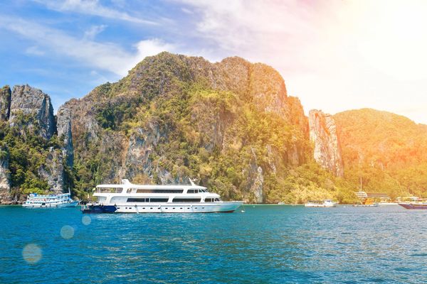Small Ship Cruise ship anchored near lush, rocky islands under a bright sunny sky.