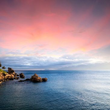 Serene ocean view at sunset with pink and orange sky hues.