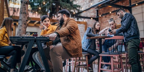 People enjoying conversations at an outdoor café with warm lighting and casual attire.