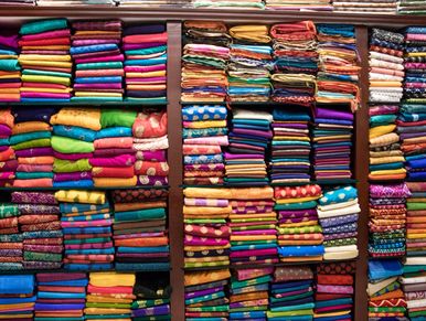 Stacks of colorful folded fabrics arranged on shelves in a textile store.