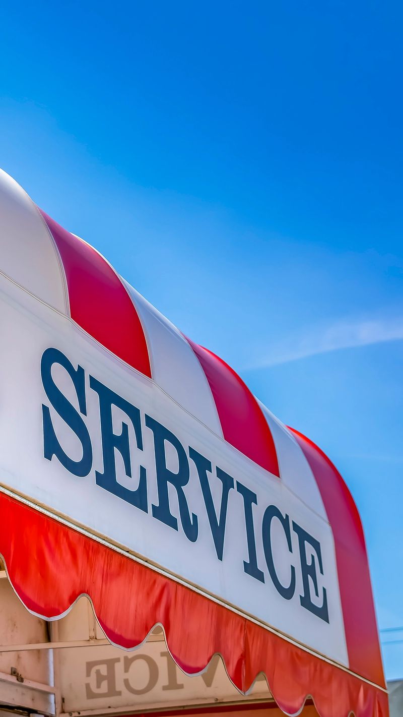 Panorama frame Car Service sign on the curved awning of a commercial brick building. Blue sky with wispy clouds can be seen in the background on this sunny day.
