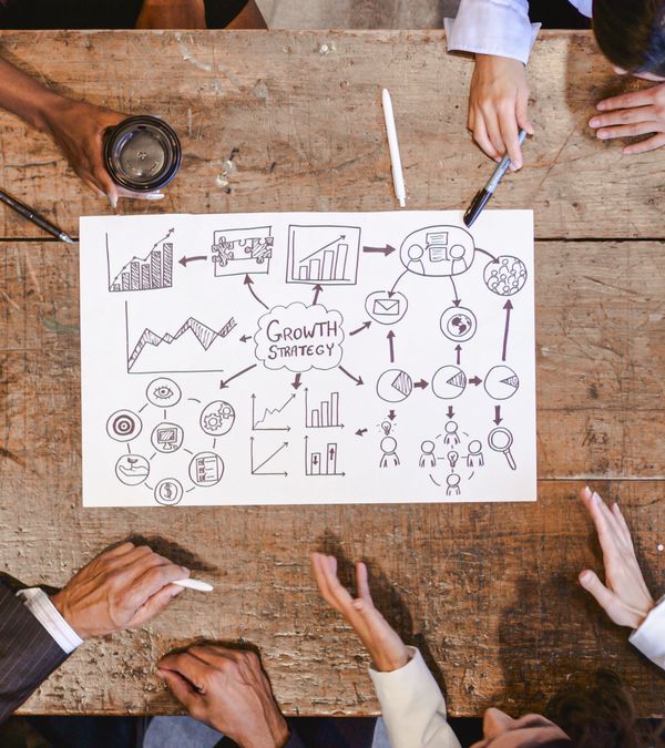 Team brainstorming growth strategy with charts and diagrams on paper.
