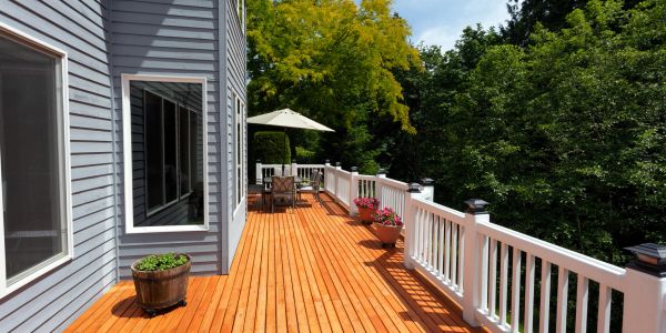 Bright wooden deck with white railing and outdoor seating.