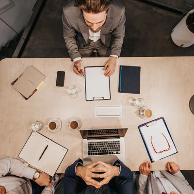 Business meeting with three professionals around a table, discussing work.