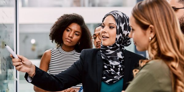 A diverse team collaborating and discussing ideas at a whiteboard.