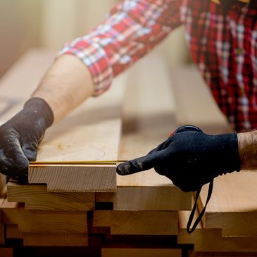Persona midiendo madera con guantes.