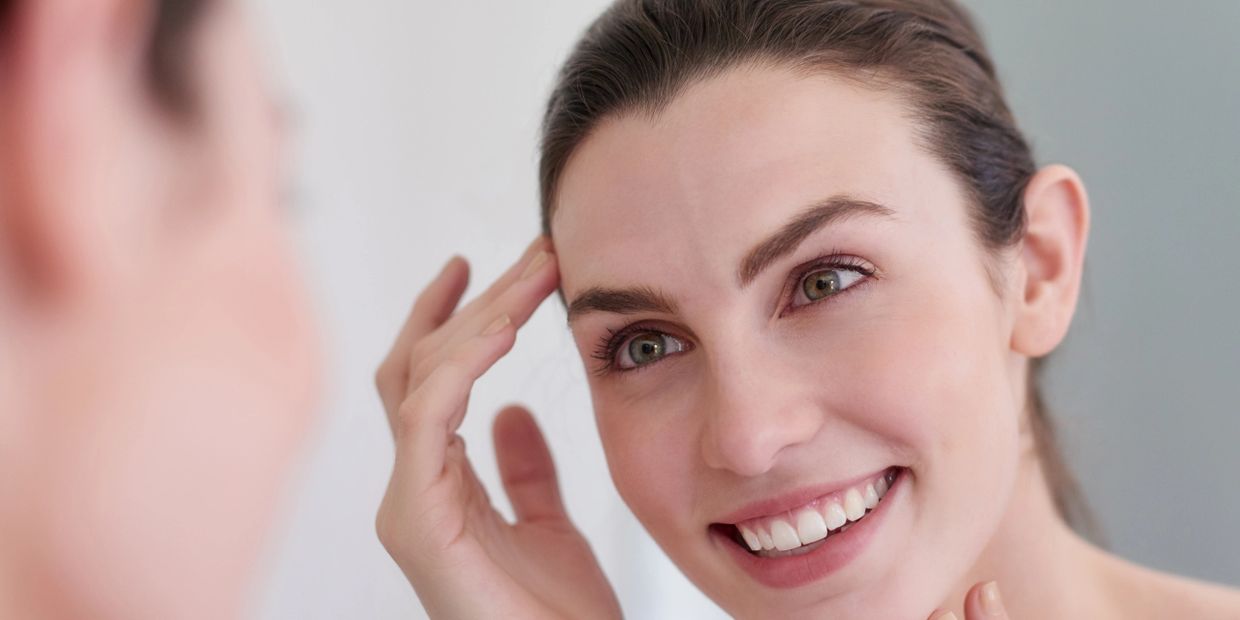 Woman smiling and looking at herself in the mirror.