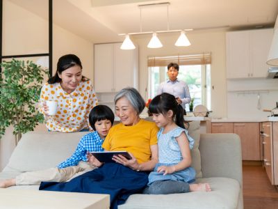 Family enjoying time together on a couch with a tablet.