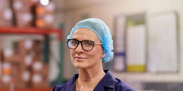 Confident female worker in protective gear at a warehouse.
