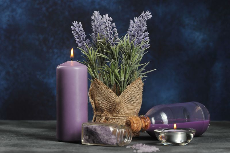 Lavender set for spa treatments. Candles lavender flowers, lavender flowers, shower gel, bath salt. Dark background. Close-up.